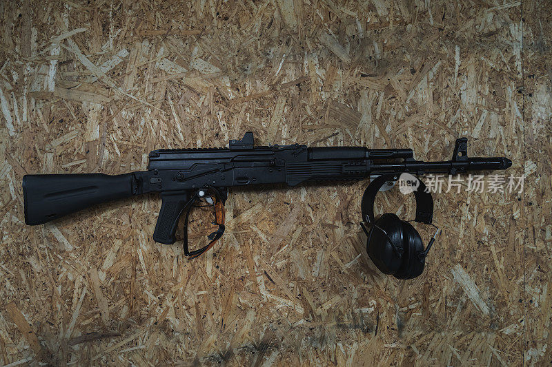墙上挂着卡拉什尼科夫AK 74m突击步枪，还有安全眼镜和耳机。